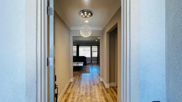 a view of a hallway with wooden floor and a living room
