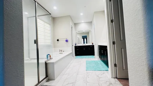 a bathroom with a tub a mirror and a shower