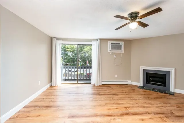 a view of an empty room with a window and a fireplace