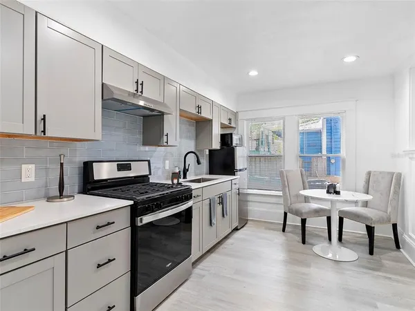 a kitchen with stainless steel appliances a stove a sink cabinets and a wooden floor