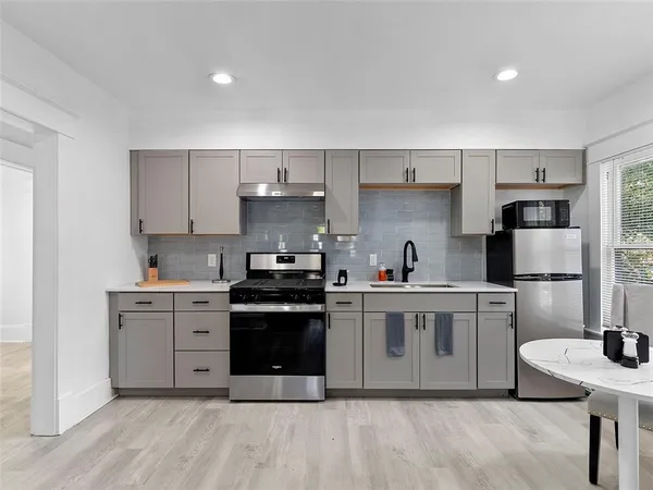 a kitchen with stainless steel appliances a stove a sink a refrigerator and white cabinets