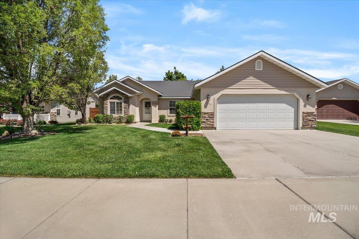 2032 Talus Loop Twin Falls, ID 83301 - Photo 3 of 43 Stucco exterior featuring stone accents, a prominent arched window, and an attached two-car garage