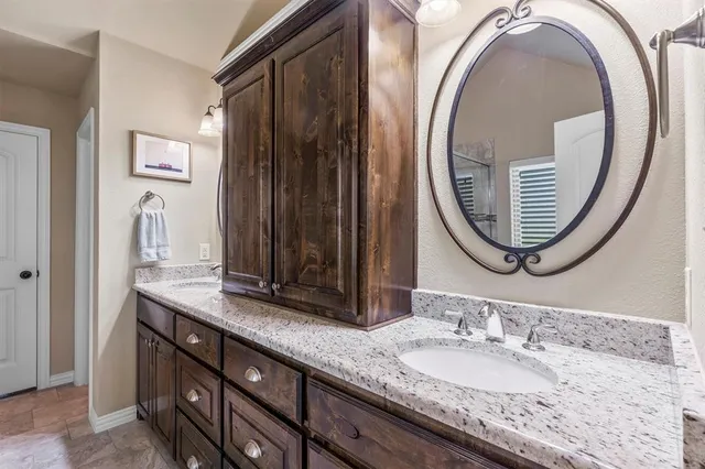 a bathroom with a granite countertop double vanity sink and a mirror
