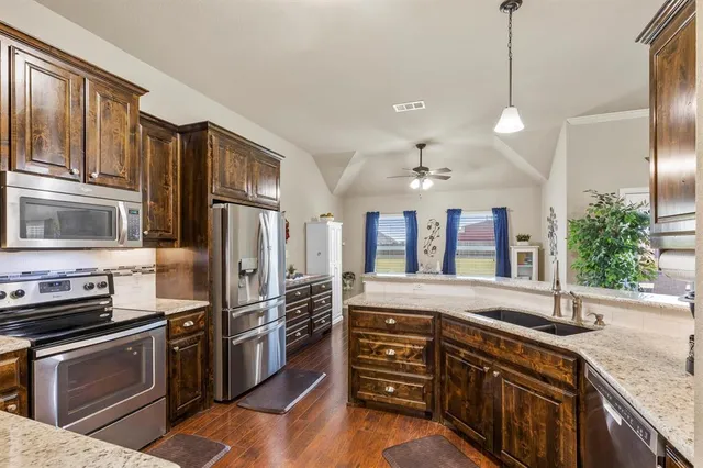 a kitchen with stainless steel appliances granite countertop a refrigerator a stove and a sink