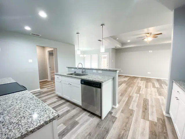 a large white kitchen with kitchen island a stove a sink dishwasher and a oven with wooden floor