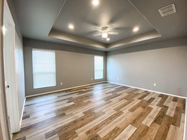 an empty room with wooden floor and windows