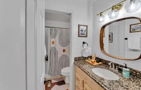 a bathroom with a granite countertop sink mirror vanity and toilet