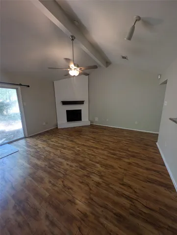 an empty room with wooden floor a ceiling fan and fireplace