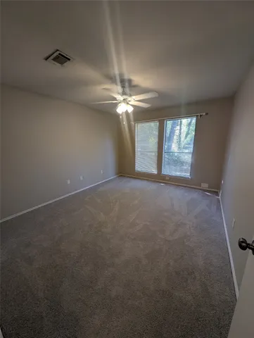 an empty room with windows and fan