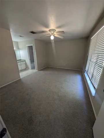 an empty room with windows and fan
