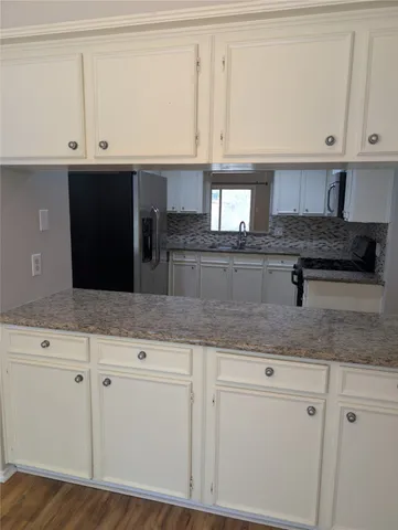 a kitchen with granite countertop white cabinets and a sink