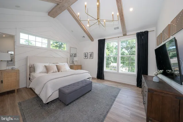 a spacious bedroom with a bed a flat screen tv and a large window