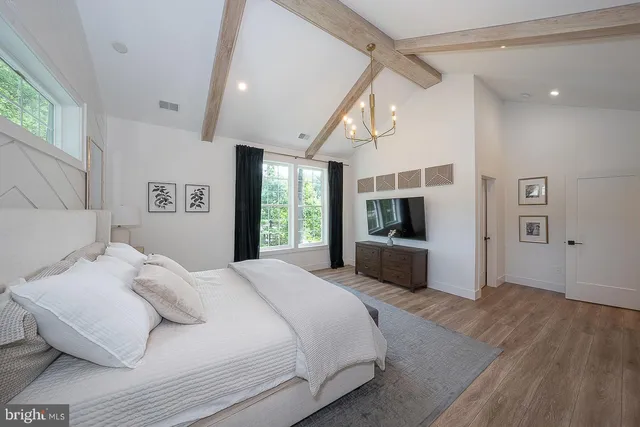 a bedroom with a large bed a flat screen tv and a window