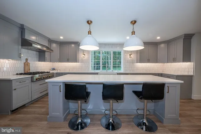 a kitchen with stainless steel appliances granite countertop a sink a stove a dining table and chairs