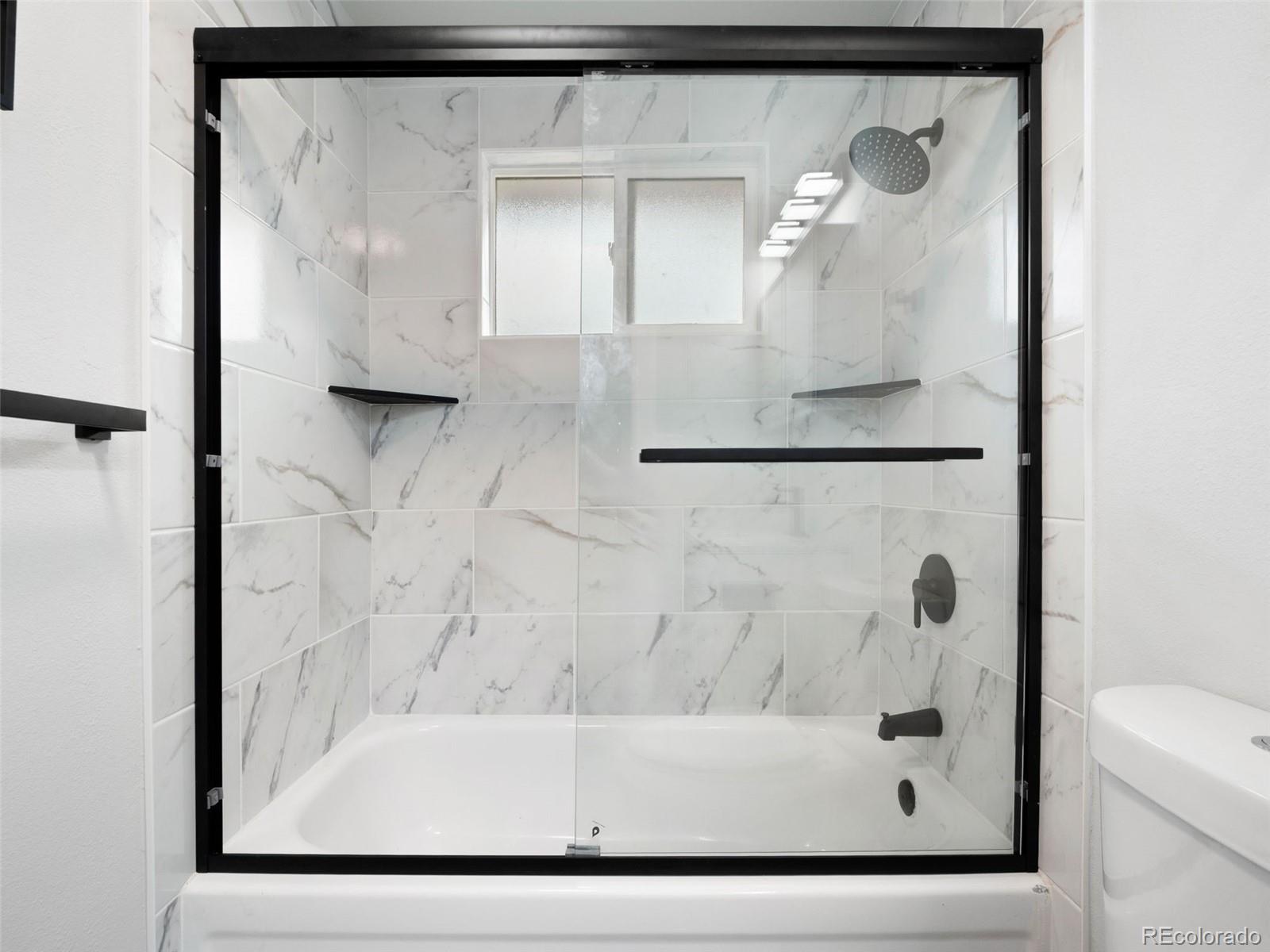 1035 6th Street Berthoud, CO 80513 - Photo 21 of 30 a bathroom with a glass shower door and a mirror