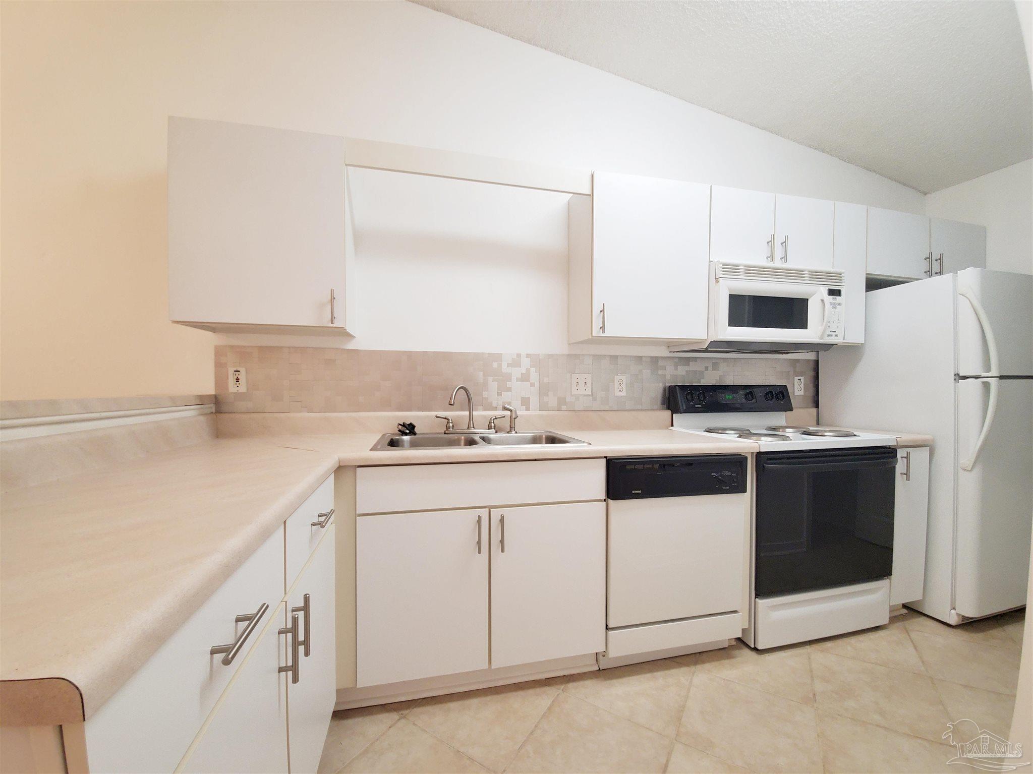 2527 Trailwood Drive Cantonment, FL 32533 - Photo 4 of 12 a kitchen with granite countertop white cabinets and white appliances