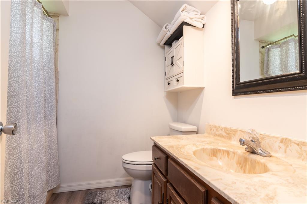 1295 Solana Road, Unit C5 Naples, FL 34103 - Photo 11 of 13 a bathroom with a granite countertop sink a toilet and a mirror