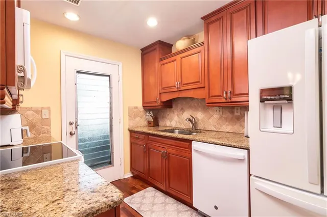 a kitchen with stainless steel appliances granite countertop a refrigerator a stove and a sink with wooden cabinets