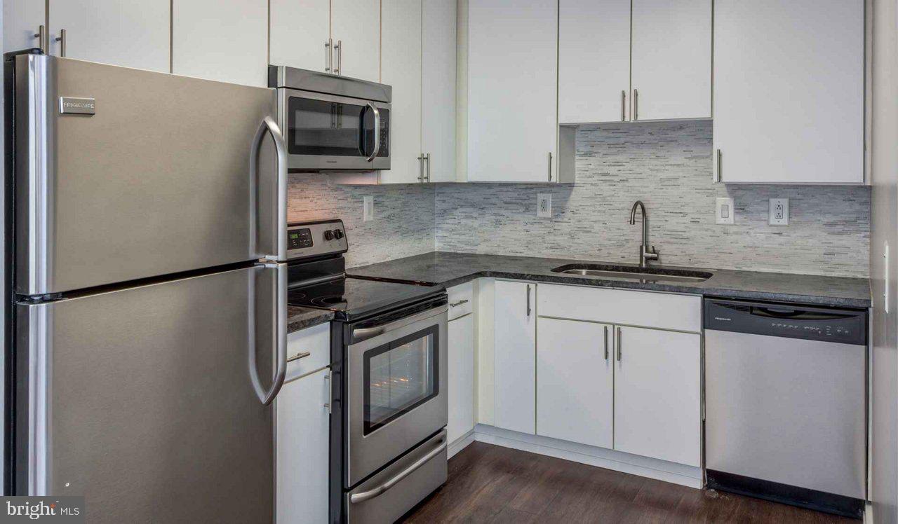 a kitchen with stainless steel appliances granite countertop a refrigerator a stove a sink and white cabinets