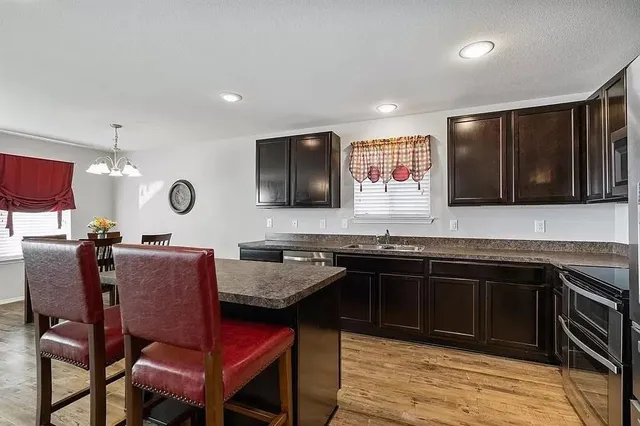a kitchen with granite countertop a sink and a stove top oven with wooden floor
