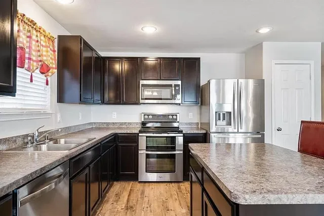 a kitchen with stainless steel appliances granite countertop a sink stove and refrigerator