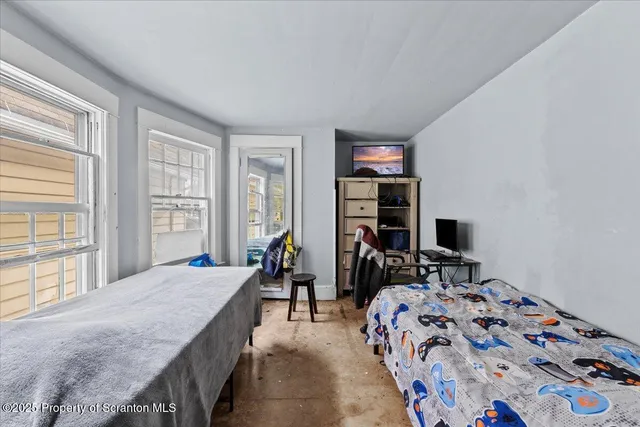 a bedroom with a bed a dresser and a large window