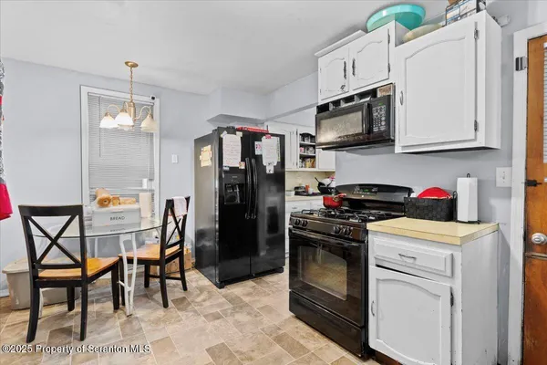 a kitchen with stainless steel appliances granite countertop a stove top oven a sink dishwasher a dining table and chairs with wooden floor