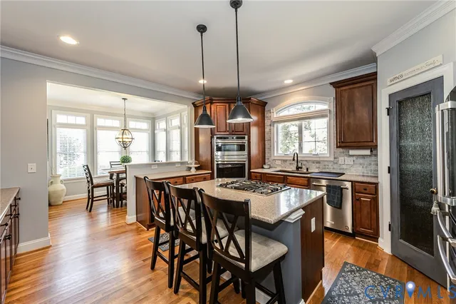 a kitchen with stainless steel appliances granite countertop a stove a refrigerator a kitchen island a table and chairs