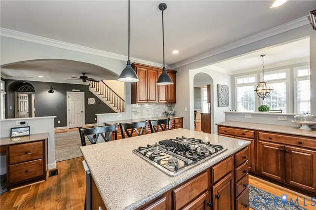 a kitchen with stainless steel appliances granite countertop a stove a sink dishwasher a dining table and chairs with wooden floor