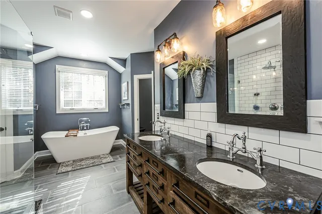 a bathroom with a granite countertop sink mirror and a bathtub