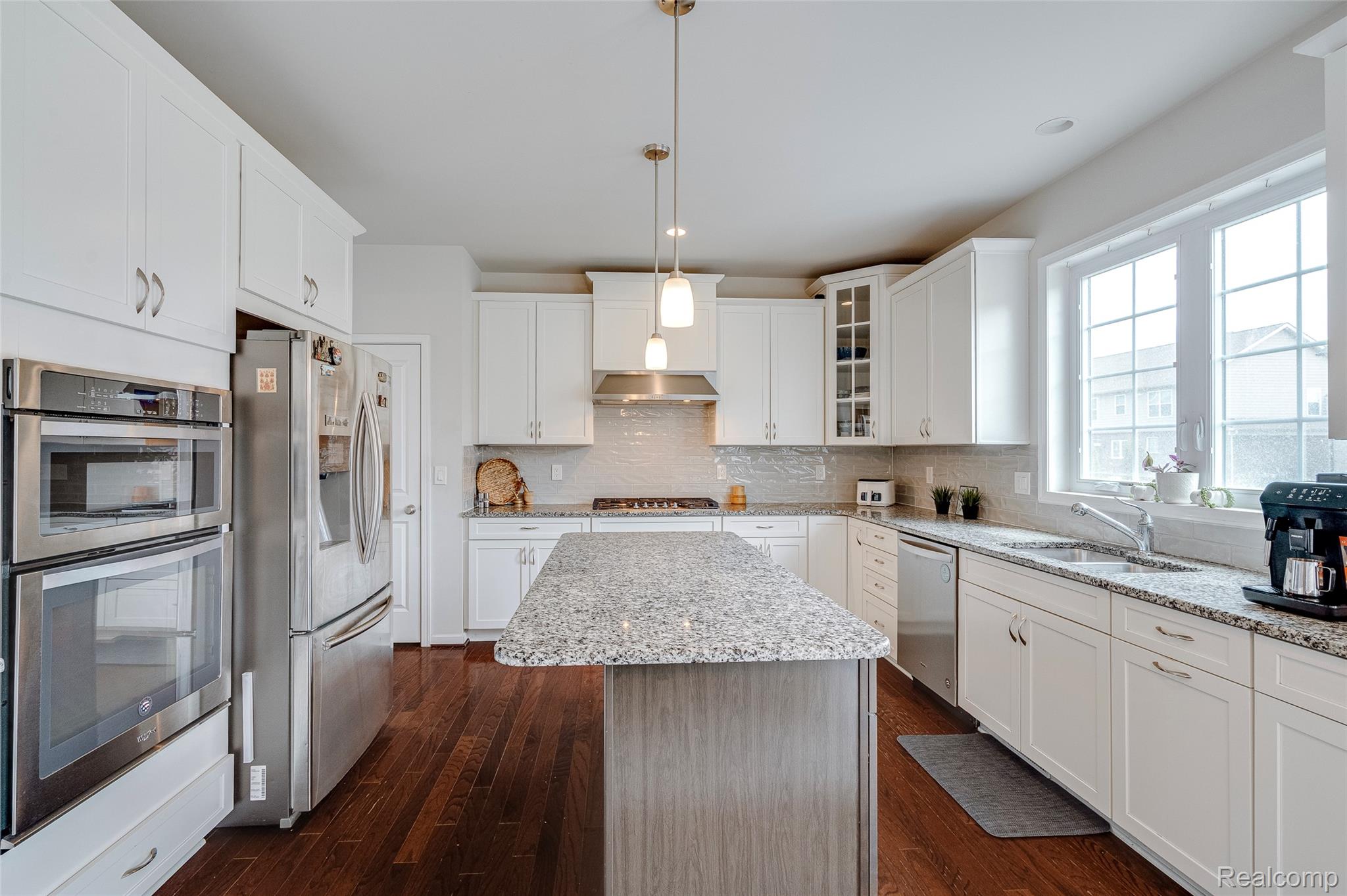51011 Rockingham Drive Canton, MI 48188 - Photo 15 of 74 Kitchen featuring stainless steel appliances, a kitchen island, light stone counters, white cabinets, and dark wood-style floors