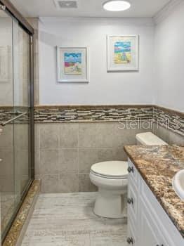 146 Boca Ciega Point Boulevard South, Unit 146 St. Petersburg, FL 33708 - Photo 3 of 14 a bathroom with a granite countertop sink a toilet and a shower