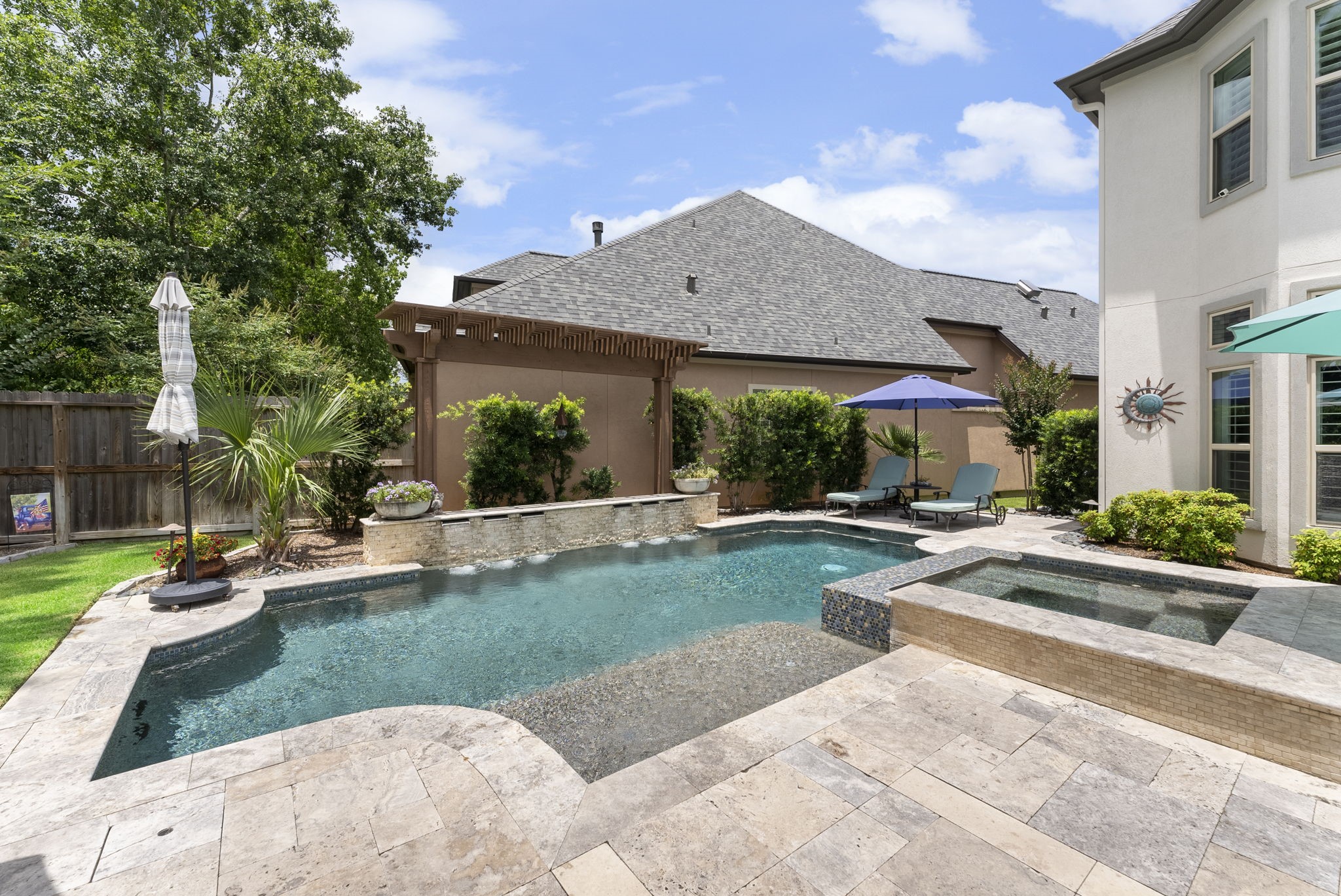 25607 Muirfield Bend Court Spring, TX 77389 - Photo 26 of 30 Private backyard oasis featuring a resort-style pool and spa, tanning ledge, tranquil water features, and multiple spaces designed for outdoor relaxation and entertaining.