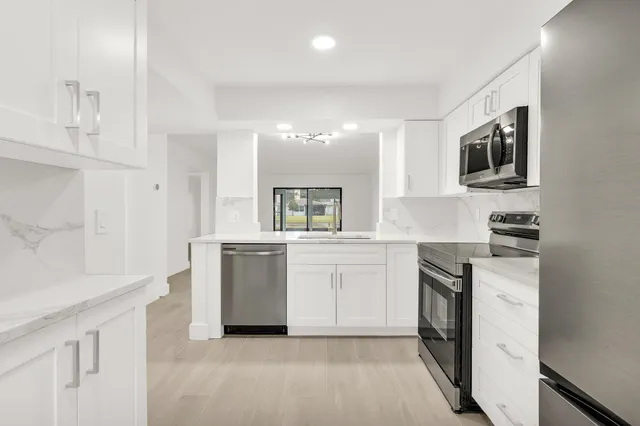 a kitchen with granite countertop white cabinets and stainless steel appliances