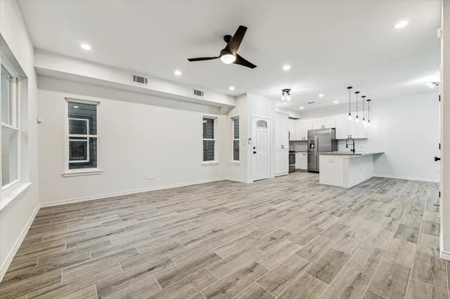a view of kitchen and empty room with wooden floor