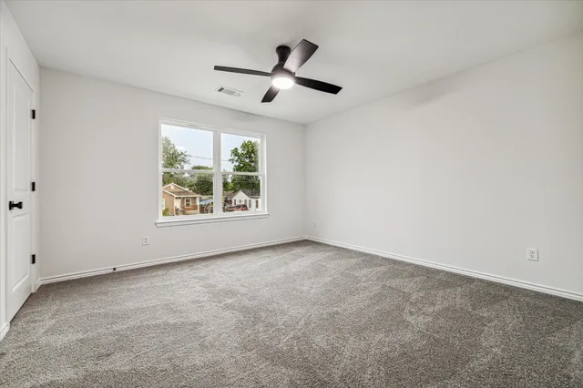an empty room with windows and ceiling fan