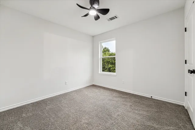 an empty room with windows and fan