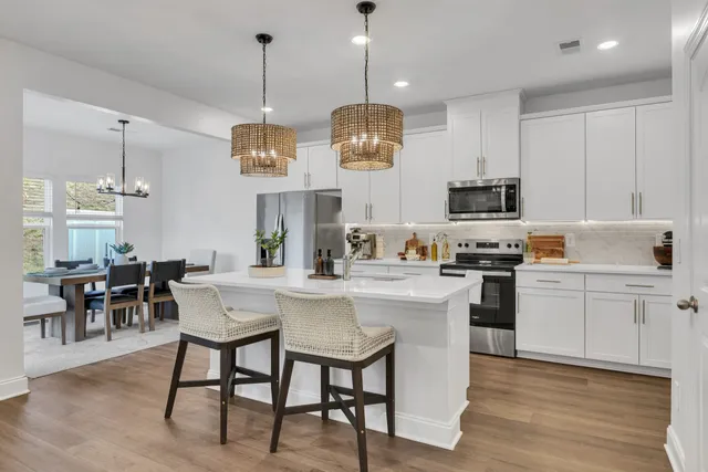 a kitchen with stainless steel appliances kitchen island granite countertop a table chairs and a stove