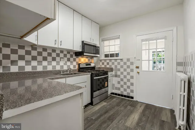 a kitchen with stainless steel appliances a stove a sink and white cabinets