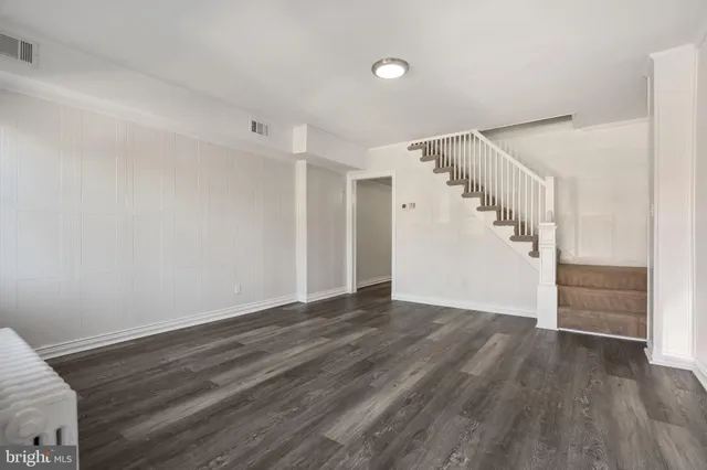 a view of an empty room with wooden floor and stairs