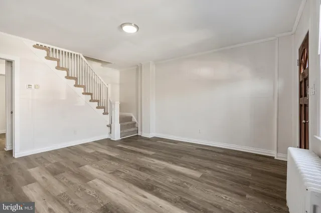 a view of an empty room with wooden floor and stairs