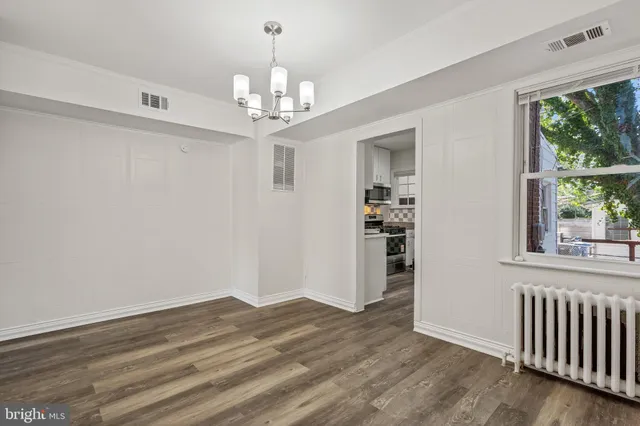 a view of a livingroom with wooden floor chandelier and windows