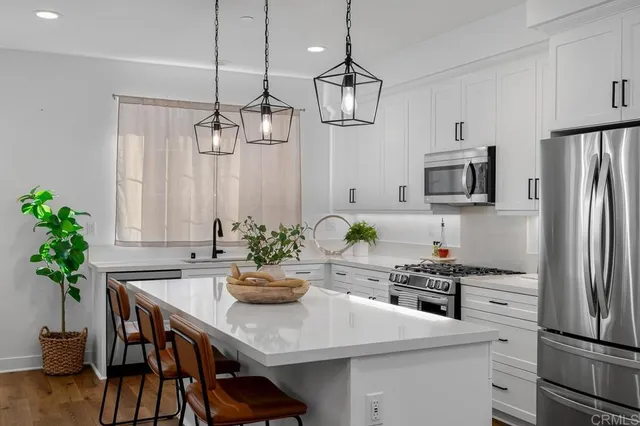 a kitchen with stainless steel appliances a table chairs refrigerator and microwave