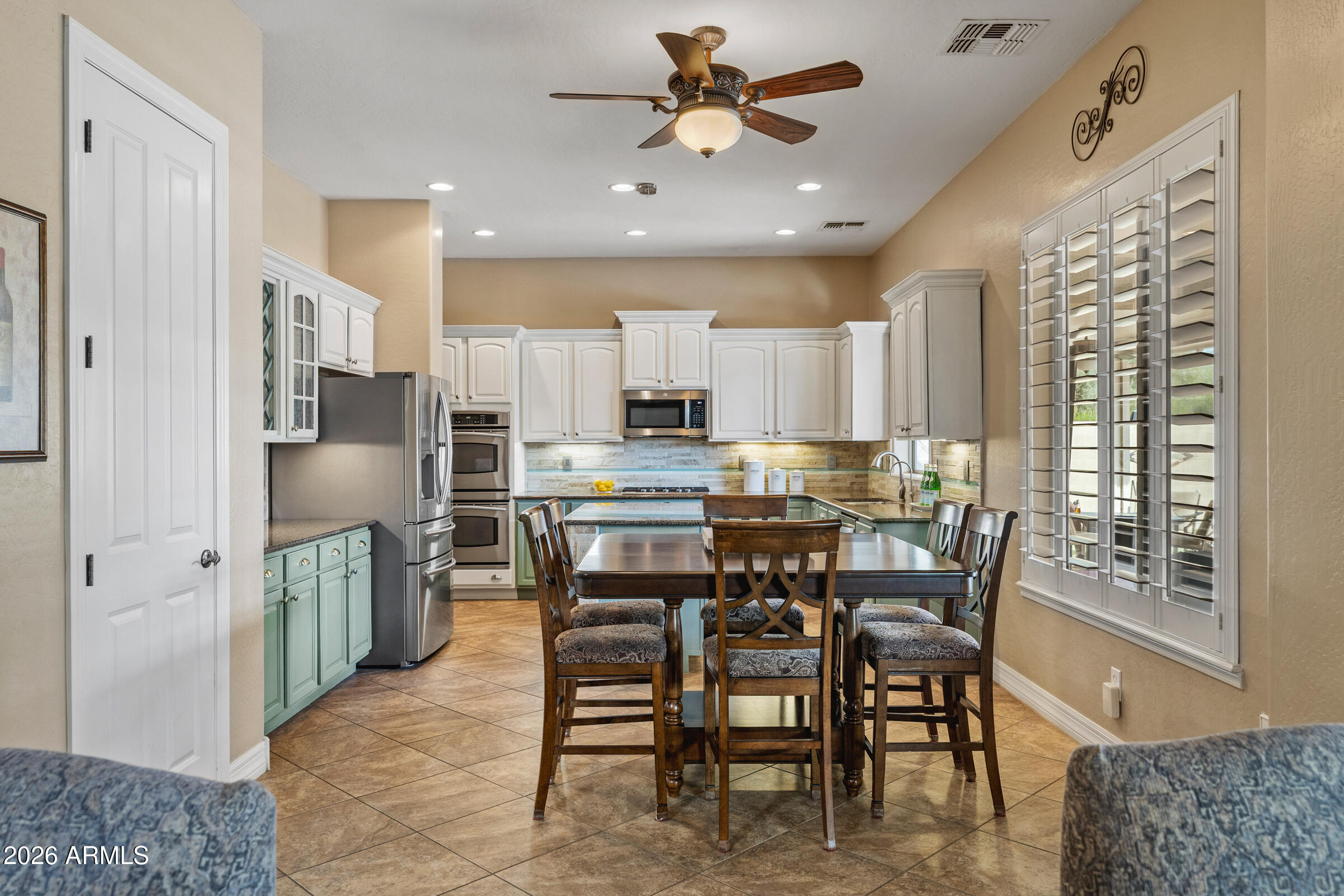 1341 East Macaw Court Gilbert, AZ 85297 - Photo 14 of 49 a kitchen with stainless steel appliances kitchen island granite countertop a table chairs and a refrigerator
