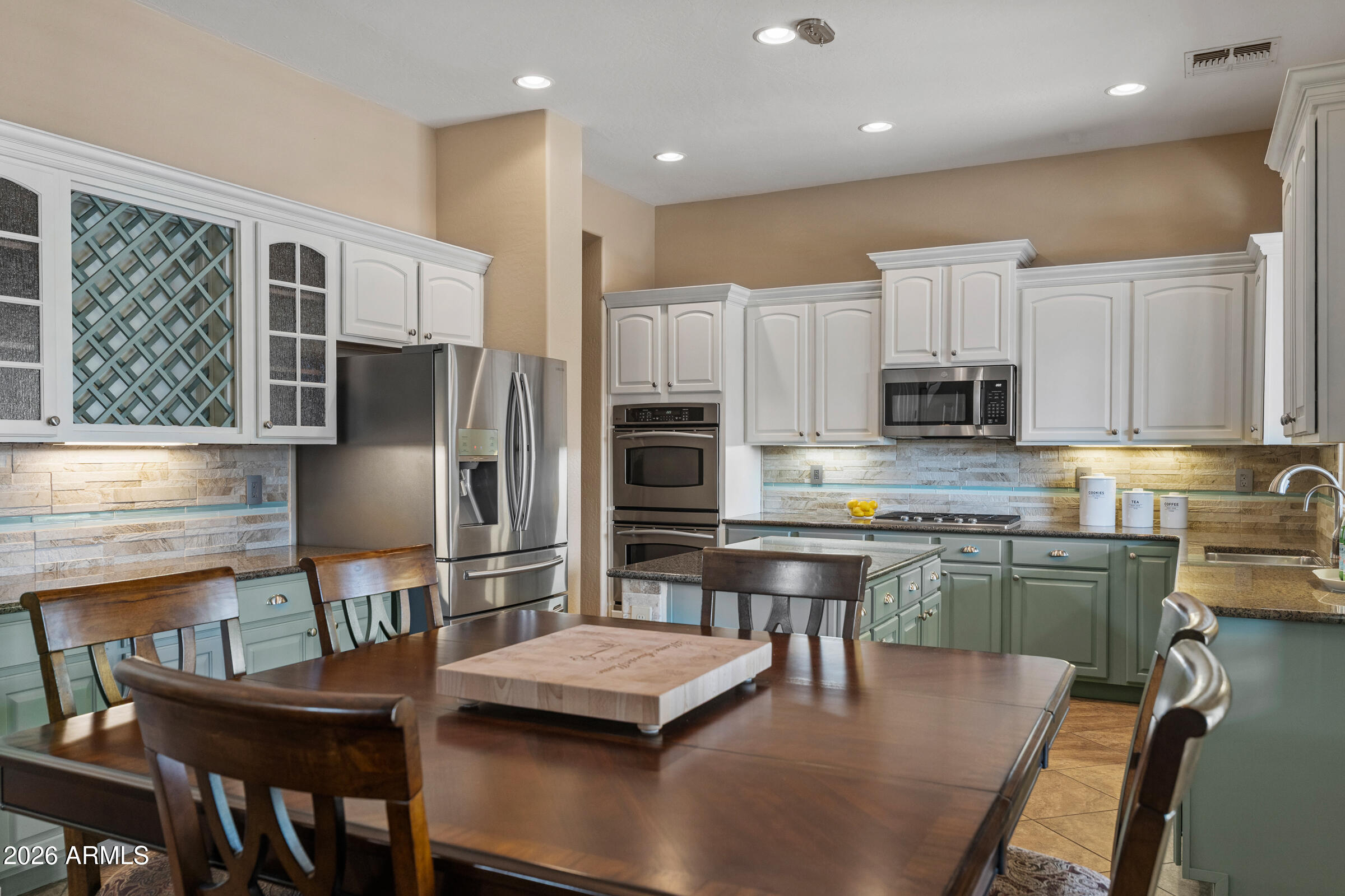 1341 East Macaw Court Gilbert, AZ 85297 - Photo 15 of 49 a kitchen with stainless steel appliances kitchen island granite countertop a table chairs microwave and sink