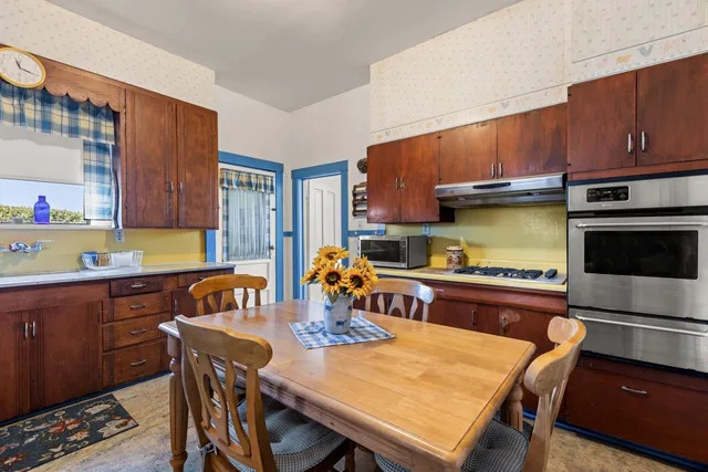 a kitchen with stainless steel appliances granite countertop a refrigerator a sink a dining table and chairs