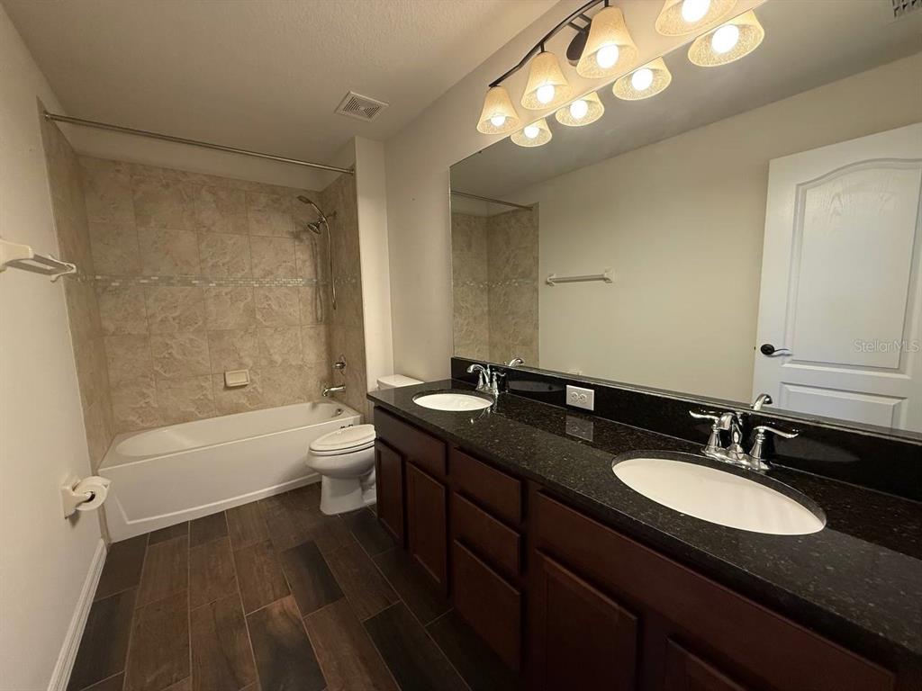 14112 Poke Ridge Drive Riverview, FL 33579 - Photo 13 of 32 a bathroom with a granite countertop sink a toilet a tub and a mirror