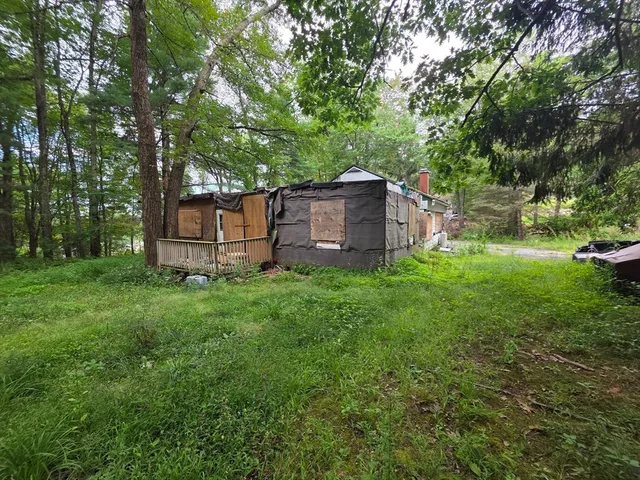 a view of a house with a big yard and large trees