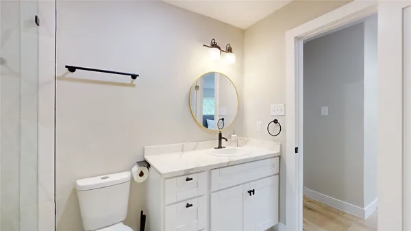 a bathroom with a shower sink vanity mirror and toilet