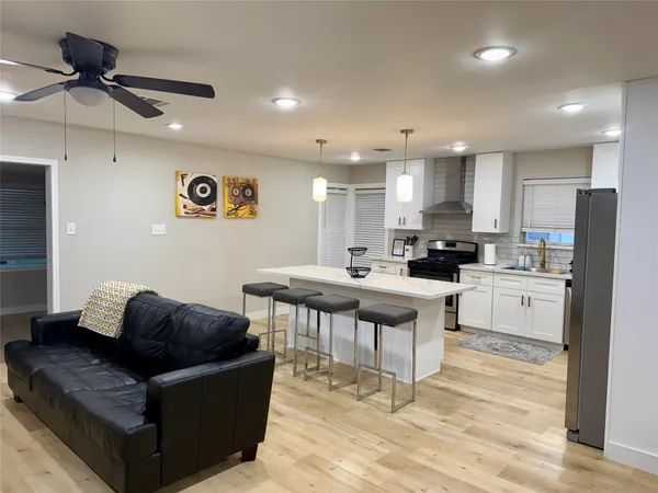 a living room with stainless steel appliances kitchen island granite countertop a couch and a view of kitchen appliances